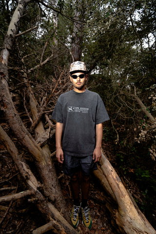 Modelo usando la camiseta Camo Division Tee SALPI, vista de cuerpo completo con pantalones y look urbano relajado