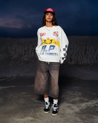 Modelo usando la camiseta La Carrera Longsleeve SALPI, vista de cuerpo completo con pantalones y estilo urbano inspirado en las carreras, look casual y cómodo