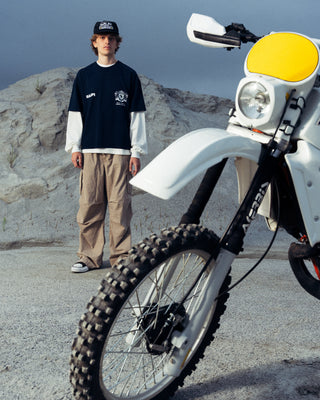 Modelo usando la camiseta Royal Tee SALPI, vista de cuerpo completo, con pantalones y look urbano relajado