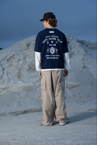 Modelo usando la camiseta Royal Tee SALPI, vista de cuerpo completo, con pantalones y look urbano relajado.