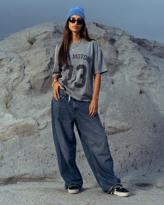 Modelo usando la camiseta Salpi Motors SALPI, vista de cuerpo completo con pantalones y estilo casual inspirado en el automovilismo